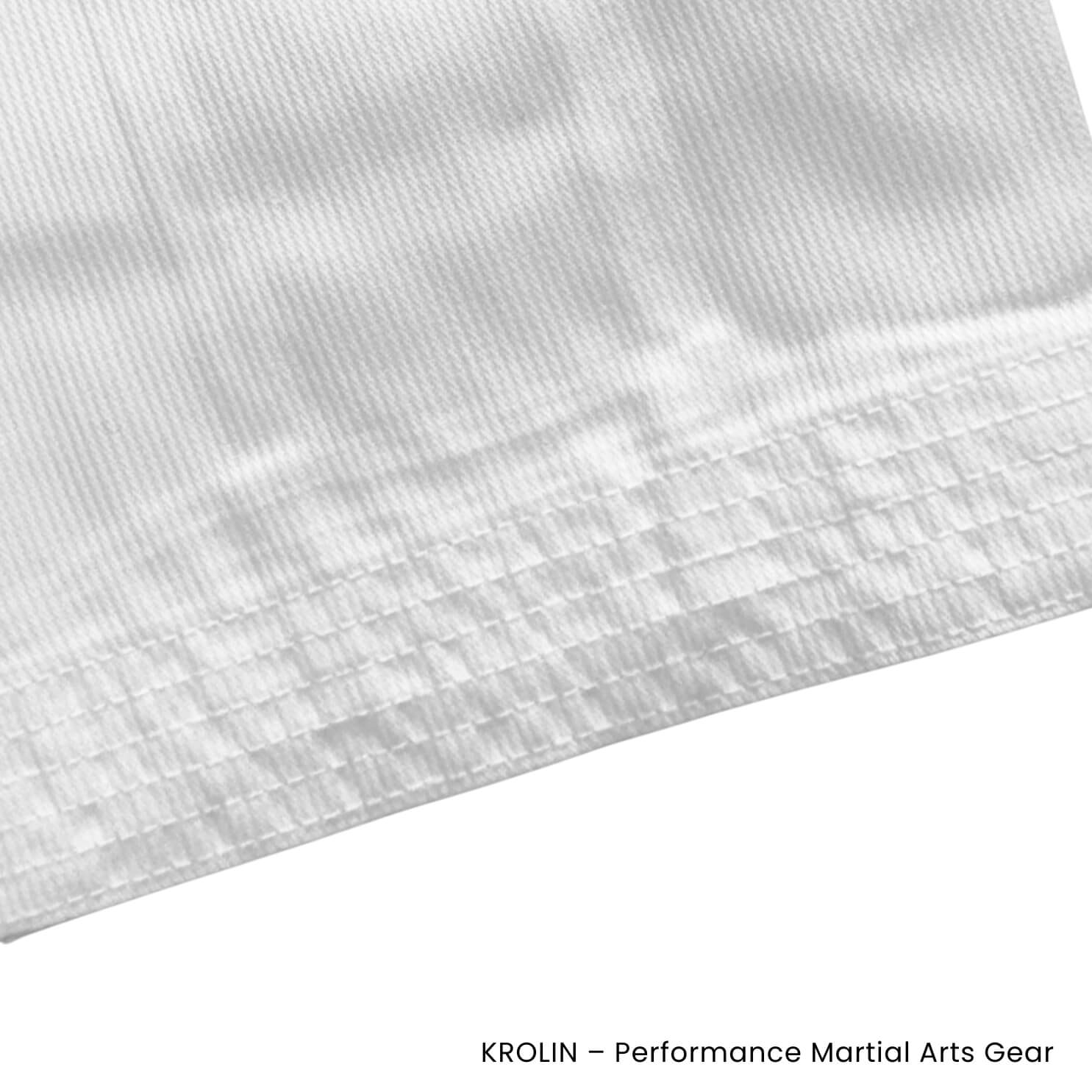 Close-up of a white martial arts uniform fabric with 'Krolin' branding.