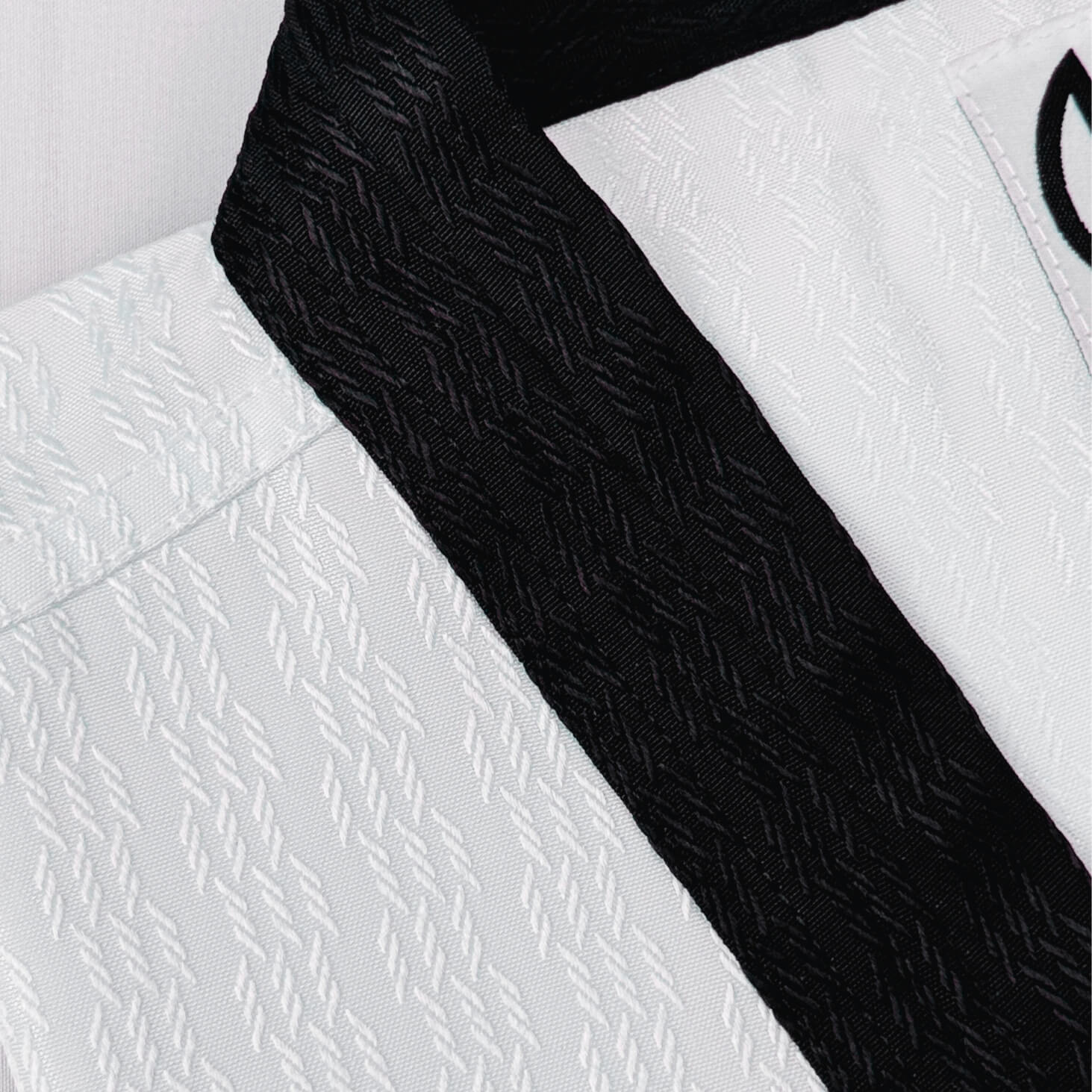 Close-up of a white martial arts uniform with a black belt on a light gray background- breathable and durable for high performance. 